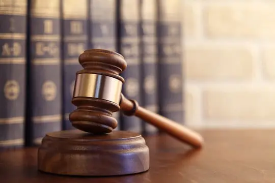 Image of a gavel on a desk with several leathbound books behind it stacked horizontally
